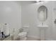 Small bathroom with pedestal sink, toilet, and an oval mirror at 390 Inflection St, Henderson, NV 89011