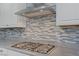 Close-up of the stainless steel gas cooktop and range hood with stylish tile backsplash at 390 Inflection St, Henderson, NV 89011