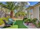 Landscaped backyard with artificial turf, seating area, mature trees, and colorful flowers at 4134 Riva De Tierra Ln, Las Vegas, NV 89135