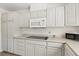 Well-lit kitchen with white cabinets, microwave, cooktop, and plenty of storage at 4573 Plaza De Vista St, Las Vegas, NV 89120