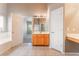 Bright bathroom with a light wood vanity, a white tub, and neutral tile flooring at 5844 Gushing Spring Ave, Las Vegas, NV 89131