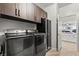 Laundry room with dark brown cabinets, stainless steel appliances, and open doorway at 5852 Ireland Ridge Ct, Las Vegas, NV 89149