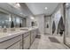 This bathroom has double sinks, a large mirror, gray cabinets, tile floor, and a walk-in shower at 600 Suncrest Peak Pl, Henderson, NV 89011