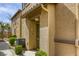 Townhome front door with a beige stucco exterior, green bushes, and an AC unit at 6255 W Arby Ave # 118, Las Vegas, NV 89118