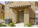 Townhome front door with a beige stucco exterior, green bushes, and an AC unit at 6255 W Arby Ave # 118, Las Vegas, NV 89118