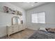 Comfortable bedroom with dresser, decor shelf, and a large window providing natural light at 6329 Sterling Ranch Way, North Las Vegas, NV 89081