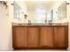 Bathroom vanity showcasing dual sinks, wood cabinets, granite counters, and large mirrors at 645 Turtleback Falls Ave, Indian Springs, NV 89018
