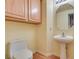 Half-bathroom with a pedestal sink, toilet, mirror, and storage above the toilet at 6582 Cartgate Ct, Las Vegas, NV 89110