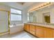 Bright bathroom boasting a soaking tub, glass shower, and double vanity with granite countertops at 6582 Cartgate Ct, Las Vegas, NV 89110