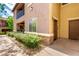 Townhouse corner exterior featuring a private patio with black railing, complemented by lush landscaping at 6868 Sky Pointe Dr # 1122, Las Vegas, NV 89131