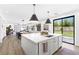 Open-concept kitchen island with seating, a stainless steel sink, and sliding glass door to the yard at 7360 Dolphine Crest Ave, Las Vegas, NV 89129