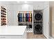 Modern closet design with white cabinets, drawers, and a stacked washer and dryer at 7569 Shadow Estates Way, Las Vegas, NV 89113