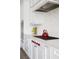 Detailed view of the white cabinetry, gas range, and decorative tile backsplash at 7569 Shadow Estates Way, Las Vegas, NV 89113