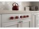 Close-up of a gas range with red knobs atop white cabinets and decorative backsplash at 7569 Shadow Estates Way, Las Vegas, NV 89113