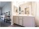 Bathroom with dual sinks, framed mirror, and vanity with a decorative chair just outside at 7704 Himalayas Ave # 204, Las Vegas, NV 89128