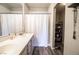 Bathroom with dual sinks, framed mirror, shower with curtain and wood-look flooring at 7704 Himalayas Ave # 204, Las Vegas, NV 89128