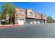 Exterior shot of garages with stone accents and second story condos above at 7704 Himalayas Ave # 204, Las Vegas, NV 89128