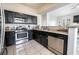 Kitchen with stainless steel appliances and black cabinets with a view to dining and living spaces at 7704 Himalayas Ave # 204, Las Vegas, NV 89128