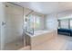Bright bathroom featuring soaking tub, glass shower, neutral tile, and large window at 7761 Boyd Ave, Las Vegas, NV 89179