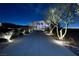 Modern home's driveway is beautifully lit at night, leading to a well-manicured landscape at 811 Magnum Cliff Ct, Henderson, NV 89012