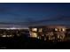 A modern home's exterior is elegantly lit at night, showcasing its architectural details and surrounding landscape at 811 Magnum Cliff Ct, Henderson, NV 89012