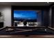 Stylish game room pool table overlooks a stunning night cityscape through open sliding glass doors at 811 Magnum Cliff Ct, Henderson, NV 89012