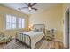 Cozy bedroom with yellow walls, hardwood floors, a window with plantation shutters, and ceiling fan at 8216 Tursi Lodge Ct, Las Vegas, NV 89131
