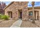 Close-up of a stone-accented entryway with a dark wood door, desert landscaping, and a welcoming pathway at 8216 Tursi Lodge Ct, Las Vegas, NV 89131