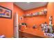 This orange home office is complete with a large wooden desk, shelving, and decor at 8216 Tursi Lodge Ct, Las Vegas, NV 89131