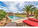 This backyard oasis includes a built-in pool, cabana, palm trees, green grass, and patio chairs at 8216 Tursi Lodge Ct, Las Vegas, NV 89131
