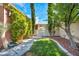 Charming backyard space with lush greenery, mature trees, and a quaint, inviting pathway at 8216 W Hammer Ln, Las Vegas, NV 89149