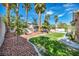 Lush backyard featuring a well-manicured lawn, mature palm trees, and decorative rock landscaping at 8216 W Hammer Ln, Las Vegas, NV 89149