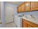 Functional laundry room with wooden cabinets, a utility sink, and modern washer and dryer at 8216 W Hammer Ln, Las Vegas, NV 89149