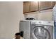 The laundry room includes a front-load washer and dryer with overhead cabinets for storage at 10135 Haymarket Peak Ave, Las Vegas, NV 89166