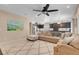 Open-concept living space with large sectional, kitchen view, tile floors, and neutral decor and large ceiling fan at 10135 Haymarket Peak Ave, Las Vegas, NV 89166