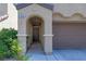 Inviting arched entryway with a covered porch leads to the front door and attached garage at 10241 Headrick Dr, Las Vegas, NV 89166