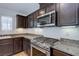 Kitchen with stainless steel range, granite counters, dark wood cabinetry, and natural light at 10241 Headrick Dr, Las Vegas, NV 89166