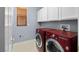 Functional laundry room with a red washer and dryer and storage cabinets at 10281 Wolves Den Ln, Las Vegas, NV 89178
