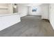 Spacious living room with gray carpet, white walls, and white tiled breakfast bar with a view out the window at 1405 S Nellis Blvd # 2087, Las Vegas, NV 89104