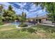 Large backyard with lush green grass, mature trees, and a sparkling pool with a safety fence at 1712 Chapman Dr, Las Vegas, NV 89104