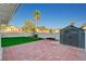 A well-maintained backyard with a storage shed, artificial grass, and brick patio at 1800 Summit Pointe Dr, Las Vegas, NV 89117