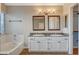 Bright bathroom featuring double sinks, granite countertop and soaking tub with tile surround at 1800 Summit Pointe Dr, Las Vegas, NV 89117