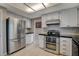 Galley kitchen featuring stainless steel appliances, white cabinets, and black countertops at 1800 Summit Pointe Dr, Las Vegas, NV 89117
