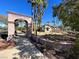The Pacific Trace community entrance features a stone arch, palm trees, and desert landscaping at 1861 Windward Ct, Henderson, NV 89012
