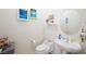 Cozy half bathroom featuring a pedestal sink, round mirror, and beach-themed decor at 2962 Gettysburg Ave, Henderson, NV 89052