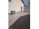 A gravel-covered backyard featuring an air conditioning unit and a metal gate, all set against a stucco wall at 3012 Silver Canyon Ln, North Las Vegas, NV 89031