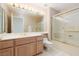 Bathroom with wooden vanity, dual sinks, large mirror, glass enclosed shower and tub at 3032 Bonnie Rock Dr, Las Vegas, NV 89134