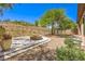 Landscaped backyard with desertscape gravel, a stone fire pit, and views of the surrounding hillside at 35 Glade Water Dr, Henderson, NV 89052