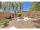 Landscaped backyard with desertscape gravel, a stone fire pit, and views of the surrounding hillside at 35 Glade Water Dr, Henderson, NV 89052