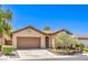 Tan single-story home featuring a well-maintained front yard, greenery, and brown garage door at 35 Glade Water Dr, Henderson, NV 89052